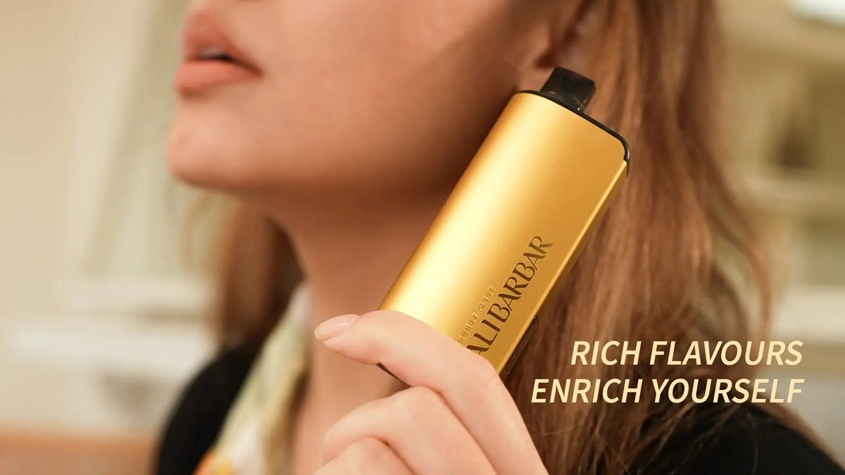 A person holding a gold metallic disposable vape device with text reading ALIBARBAR.